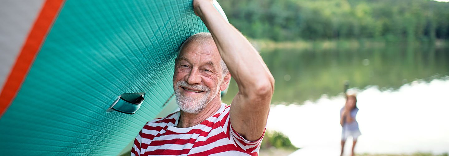 smiling senior man holding paddle board